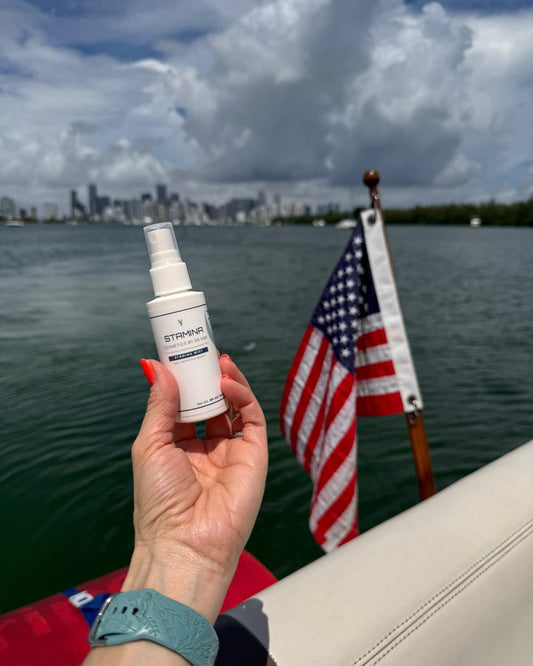 Stamina Mist held up on the water with the Miami skyline and an American flag behind it